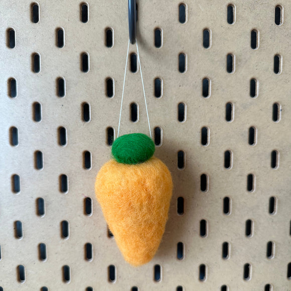 Felted carrot ornaments in a wooden crate.